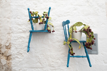 Blue chairs on a white wall with flower pots in the Ostuni Puglia, Italy