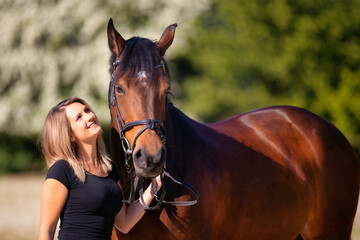 Obraz premium Young girl stands to the right of her horse and looks him lovingly in the eyes with a smile..