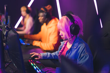 Fototapeta na wymiar young pink-haired girl participating in video games tournament cyber sport concept medium closeup neon lights indoors. High quality photo
