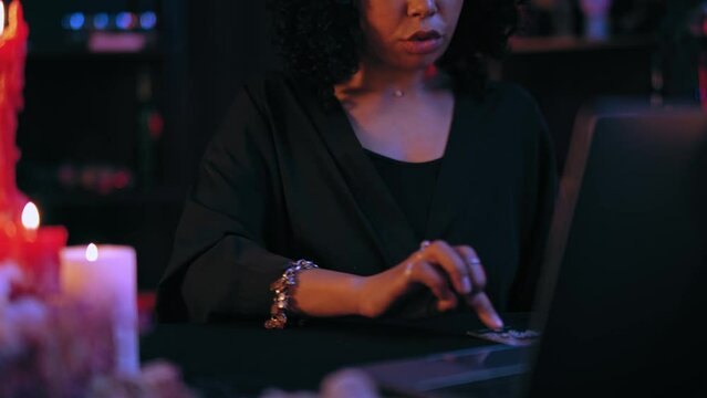 Female oracle laying out tarot cards in front laptop, consulting client online