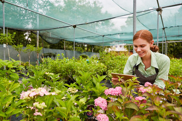 Young gardener photographs flowers with tablet PC