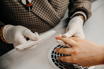 Woman in nail salon receiving manicure, hands closeup. Professional manicure in beauty salon. Hygiene and care for hands. Beauty industry concept.