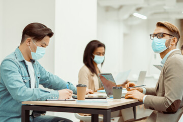 Obraz premium Two men and woman working at the table in the office