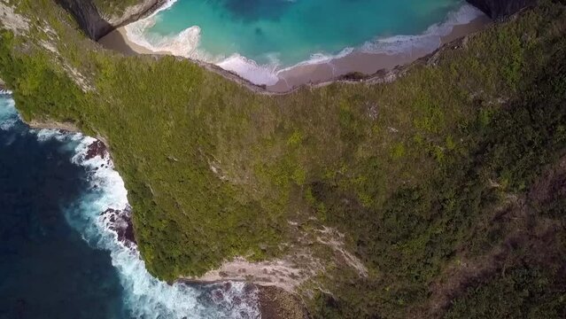 Dramatic aerial view flight high bird's eye view drone shot ofer edge cliff big waves 
Kelingking Beach at Nusa Penida in Bali Indonesia Jurassic Park. Cinematic nature view above by Philipp Marnitz