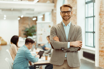 Smiling man standing in a coworking space and clasped his hands