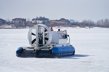 The airboat returns to the shore after patrolling on the thin ice of a frozen river.