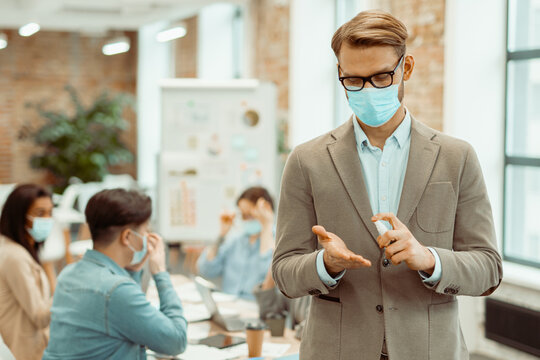 Male employee sanitizing hands in the office