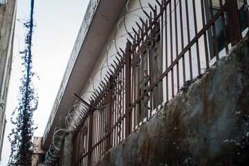 Barbed wire enclosure outside a building with metal grill.