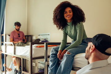 young people in dormitory spending free time - Brazilian girl with curly hair sitting on bunk bed...