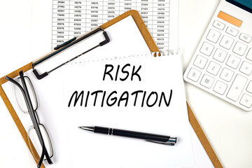 Text RISK MITIGATION on the white paper on clipboard with chart and calculator