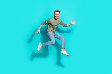 Fototapeta na wymiar Full size photo of millennial blond guy jump wear sweater jeans sneakers isolated on turquoise background