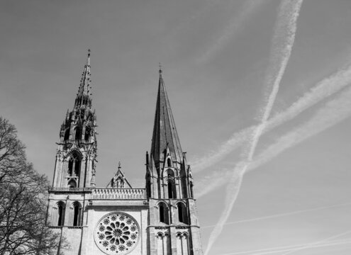 Cathedral of Chartres and the traces of the planes in the sky. Chartres, France. Aged photo. Black and white.