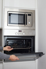 Fototapeta premium built in wall oven and microwave cabinet. Male hands open oven