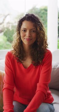 Vertical video portrait of happy biracial woman smiling to camera in living room