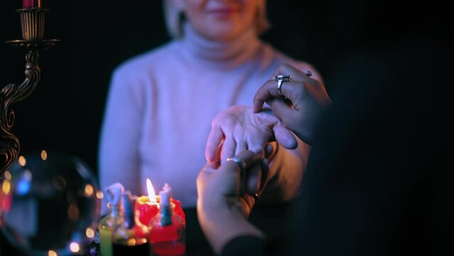 Chiromancer reading lines on happy woman's palm to predict future, palmistry art