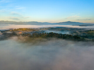 The rays of dawn over the fog in the Ukrainian Carpathians. Aerial drone view.