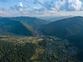 Green slopes of Ukrainian Carpathian mountains in summer. Cloudy day, low clouds. Aerial drone view.