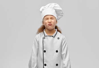 cooking, culinary and profession concept - little girl in chef's toque and jacket over grey background