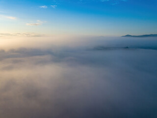 Obraz premium The rays of dawn over the fog in the Ukrainian Carpathians. Aerial drone view.