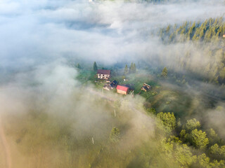 Fototapeta premium Mountain settlement in the Ukrainian Carpathians in the morning mist. Aerial drone view.