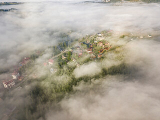 Mountain settlement in the Ukrainian Carpathians in the morning mist. Aerial drone view.