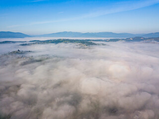 Flight over fog in Ukrainian Carpathians in summer. Mountains on the horizon. Aerial drone view.