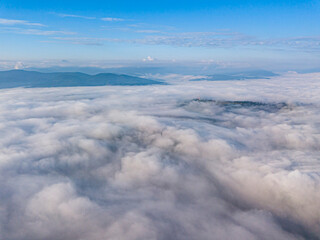 Obraz premium High flight above the clouds in the mountains. Aerial drone view.