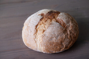 Loaf of freshly baked homemade artisan bread on a wooden surface. Selective focus.