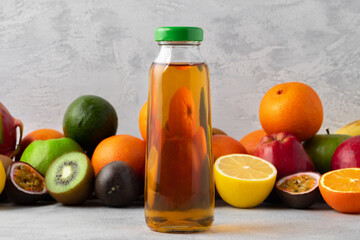 Various fruits and freshly squeezed fruits juice in bottle on gray background