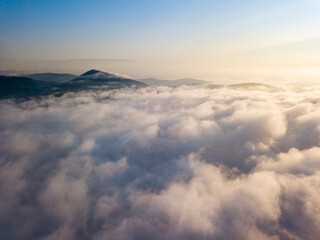 Flight over fog in Ukrainian Carpathians in summer. Mountains on the horizon. Aerial drone view.