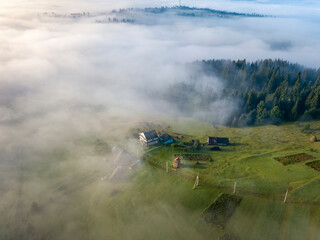 Fototapeta premium Mountain settlement in the Ukrainian Carpathians in the morning mist. Aerial drone view.