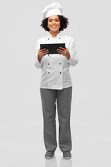 cooking, culinary and people concept - happy smiling female chef in toque and and jacket with tablet pc computer over grey background