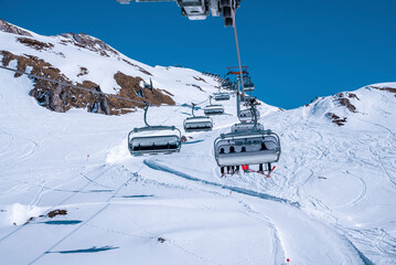 St. Anton am Arlberg. March 10, 2022. Skiers sit in chairlifts on mountain slope at ski resort...