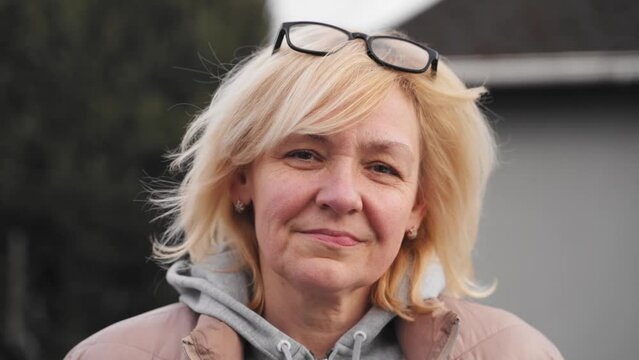 Close up video portrait of blonde caucasian mid age woman outdoors on a windy cold day