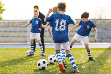 Obraz premium Physical Education Class for School Children. Soccer Education for Young Boys. Young Coach With Kids in Team on Training Unit. Youth Team Coach Training School Boys in Football Soccer