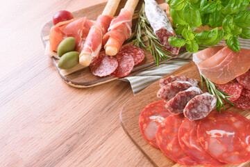Traditional Italian antipasti on wooden table background. Charcuterie plate with different types of sausages - salami, bresaola, proscuitto served with olives and grissini. Selective focus