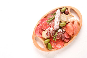 Wooden charcuterie board with different types of sausages - salami, bresaola, proscuitto served...