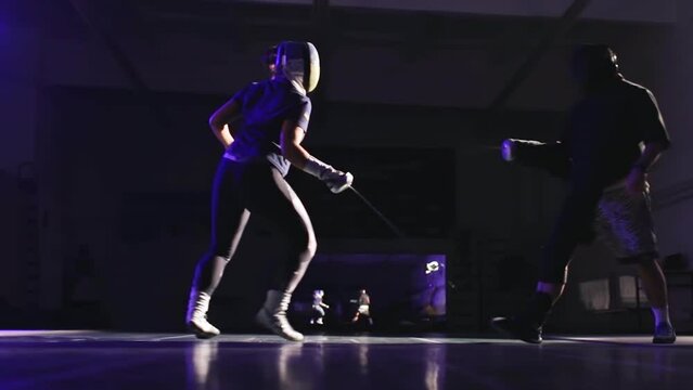 Fencing. athlete and coach practice technique. Dressed in fencing clothes and helmets. In the hands of swords, rapiers