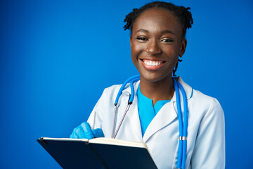 Black female doctor student wearing a lab coat with book