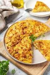 Frittata or potato pie in a ceramic plate on a light culinary background. Traditional Italian delicious homemade egg dish on the kitchen table	