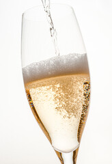 bubbles and foam of different sizes and volumes from golden-colored sparkling wine when pouring a drink into a glass on a light background in a close-up studio