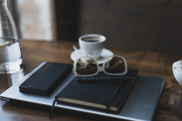 Desktop with laptop, notepad, phone and sunglasses