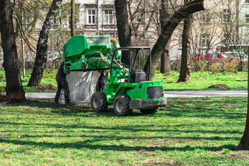 Municipal workers empty the container of the cleaning machine from the leaves, branches and garbage...