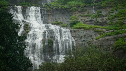 Beautiful natural waterfall through a beautiful roadside green mountain.