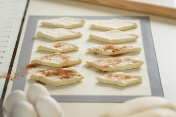 Baking dough blanks sprinkled with cinnamon on a silicone baking mat