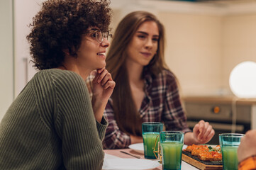 Group of friends enjoying dinner while sitting at the kitchen table together
