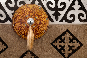 Antique national kazakh wall with shield, decoration in gold color on the background of a carpet with patterns