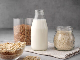 Assortment of organic vegan non-dairy milk from oatmeal, rice, buckwheat in a glass bottle on a gray background. The concept of beverages, healthcare, diet and nutrition. Copy space. Close up. Healthy