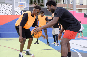 Black men playing basketball on sports ground