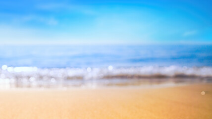 Fototapeta na wymiar Blurred background of tropical beach with light surf, blue sky and golden sand.